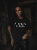 Kobieta prezentująca czarny t-shirt damski Stronger Than The Storm z białym nadrukiem, zestawiony z czarnymi spodniami w rockowym stylu.