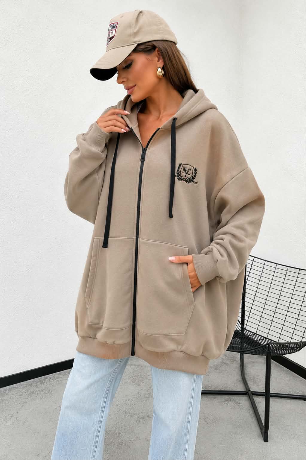 Damska bluza oversize w kolorze fango z kapturem i zamkiem błyskawicznym. Gruba rozpinana bluza z haftem Social Club, dużymi kieszeniami i wygodnym fasonem oversize.