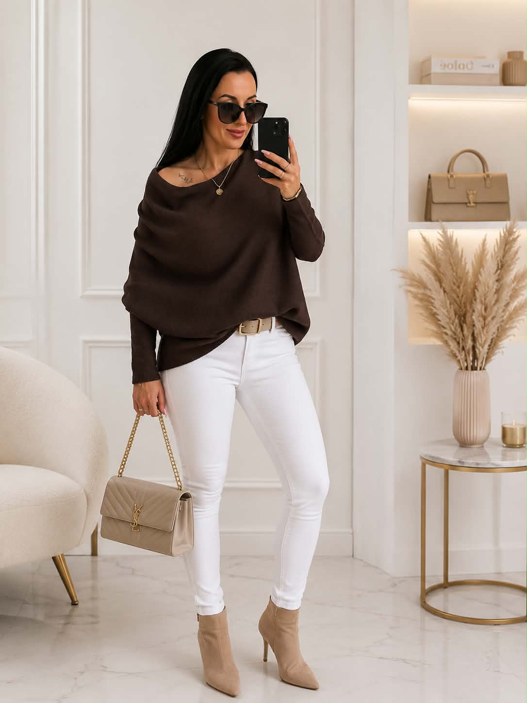 Elegancki damski sweter oversize z dodatkiem kaszmiru w kolorze czekoladowym, zestawiony z białymi spodniami i beżową torebką – stylizacja idealna na co dzień i do pracy.