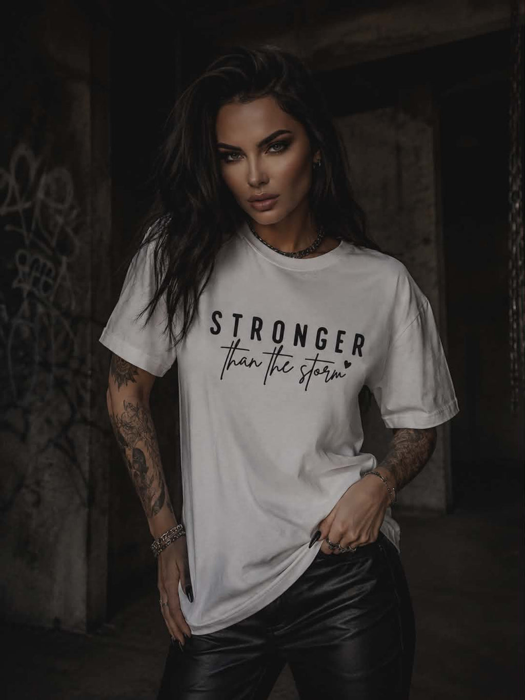 Biała koszulka damska Stronger Than The Storm z czarnym nadrukiem, wykonana z miękkiej bawełny, w modnej miejskiej stylizacji.
