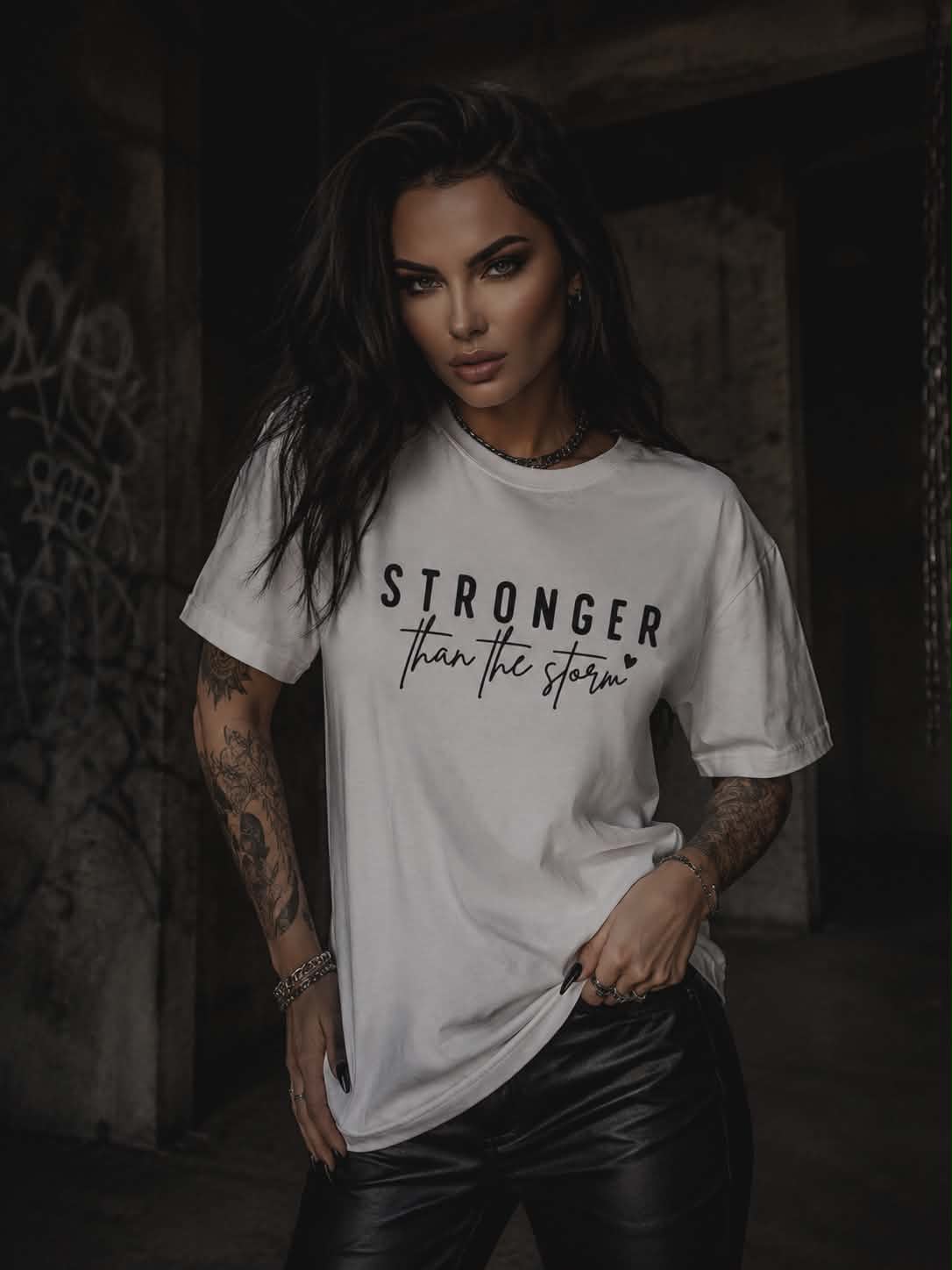 Biała koszulka damska Stronger Than The Storm z czarnym nadrukiem, wykonana z miękkiej bawełny, w modnej miejskiej stylizacji.
