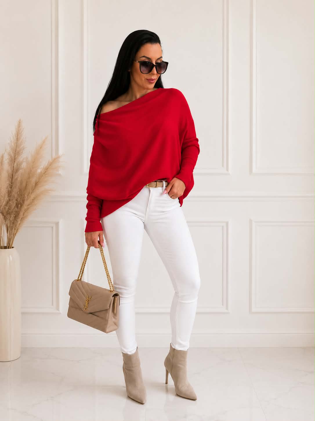 Elegancki damski sweter oversize z dodatkiem kaszmiru w czerwonym kolorze, zestawiony z białymi spodniami i beżową torebką – stylowa propozycja na co dzień i wyjątkowe okazje.