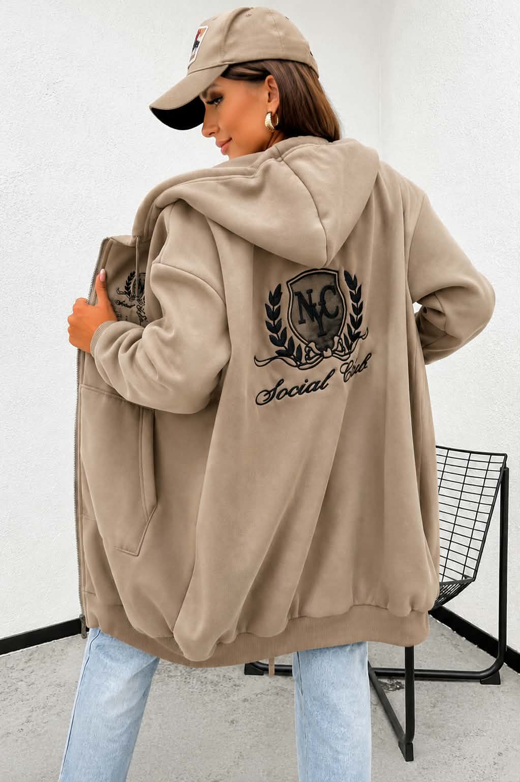 Damska bluza oversize w kolorze fango z dużym haftem Social Club na plecach. Gruba rozpinana bluza z kapturem i kieszeniami wykonana z wysokiej jakości bawełny.