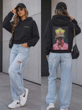 Modna czarna bluza damska La Perla z kapturem i efektownym nadrukiem na plecach, zestawiona z jasnymi jeansami w stylu streetwear.
