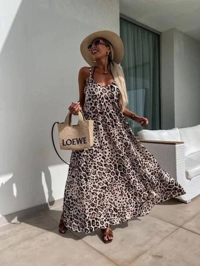 Kobieta w zwiewnej sukience maxi w panterkę, letnia stylizacja z kapeluszem, okularami i plecioną torebką, modny look wakacyjny boho