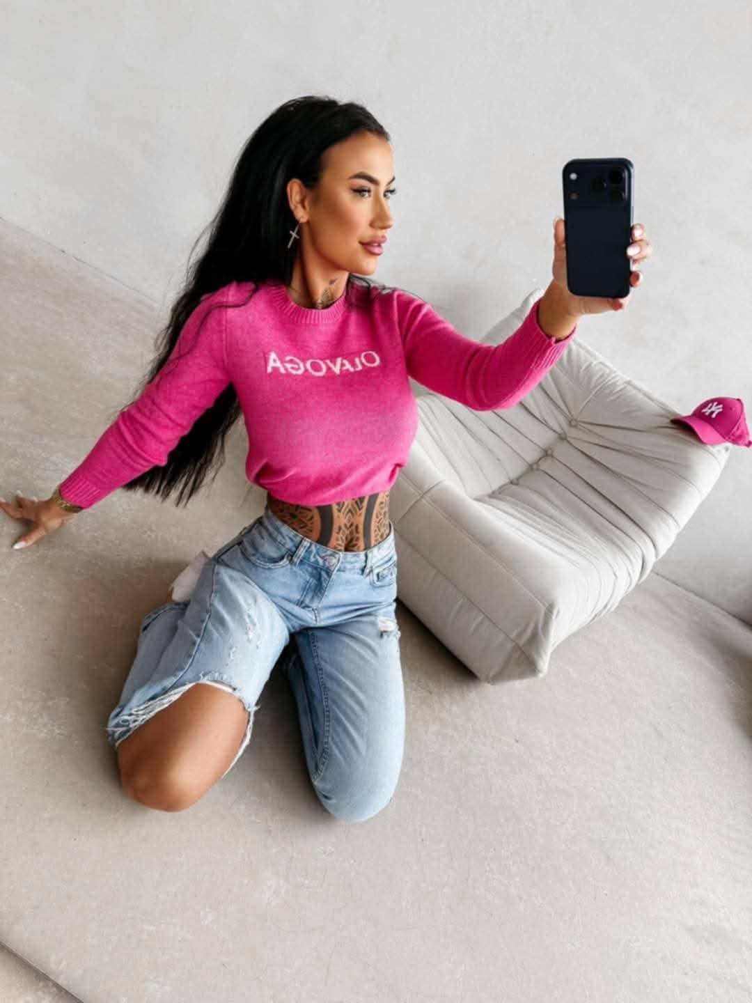 Dopasowany sweter damski OLAVOGA w kolorze fuksji, długi rękaw, styl casual, modelka w jeansach, nowoczesny look streetwear premium