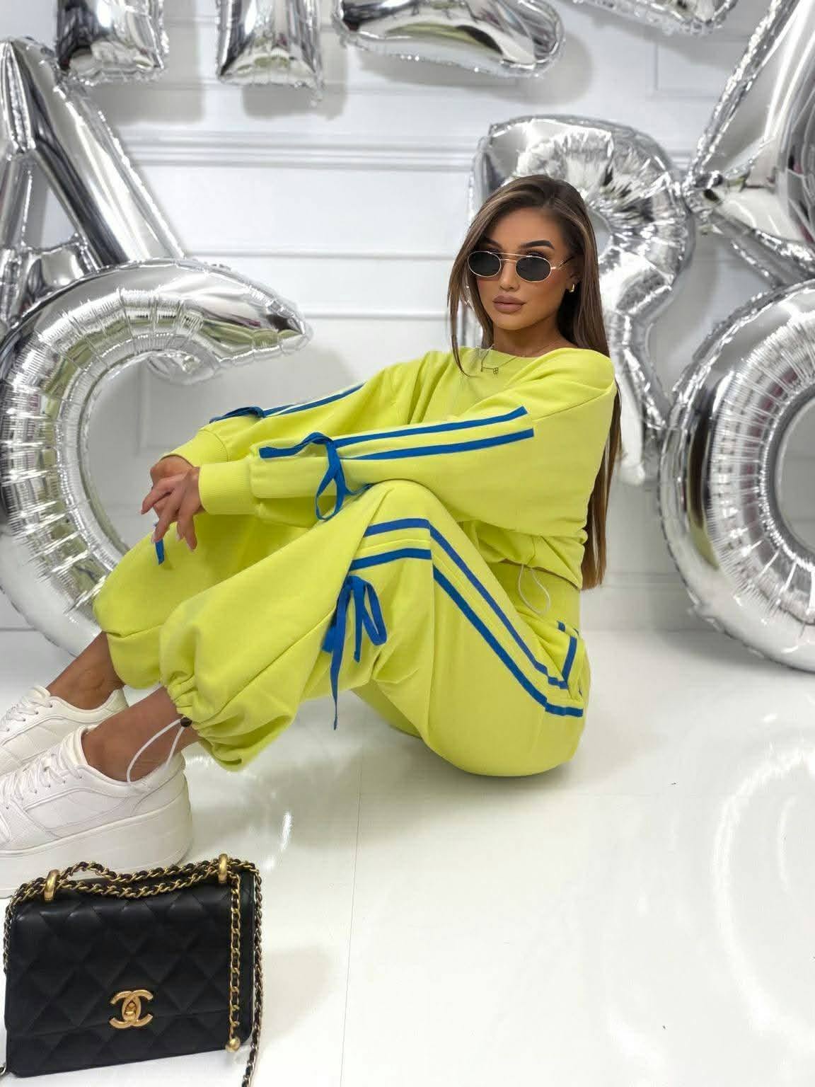 Stylowy dres damski Millagro w kolorze limonkowym, oversize komplet z niebieskimi lampasami, sportowy casual look z białymi sneakersami i modnym streetwearowym stylem
