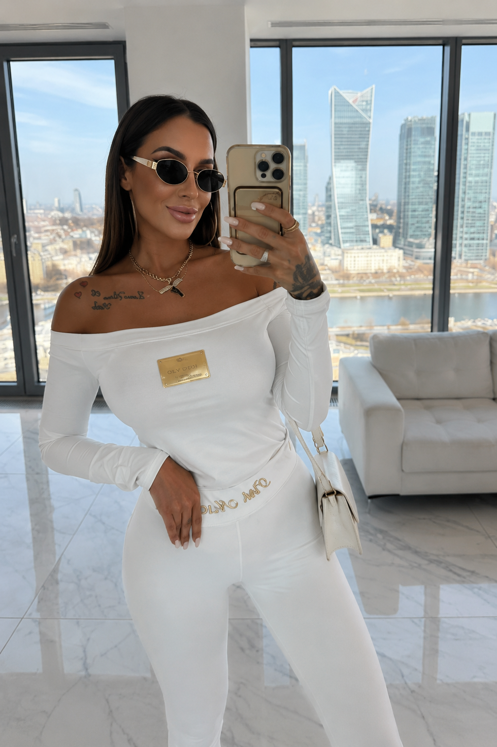 Kobieta w białej bluzce hiszpance premium i dopasowanych legginsach w eleganckim stylu luxury.