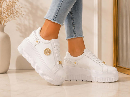 Białe sneakersy damskie Goodin ze skóry naturalnej na grubej platformie, prezentowane na nogach. Modne buty z ozdobnymi złotymi detalami, idealne do jeansów i codziennych eleganckich stylizacji.
