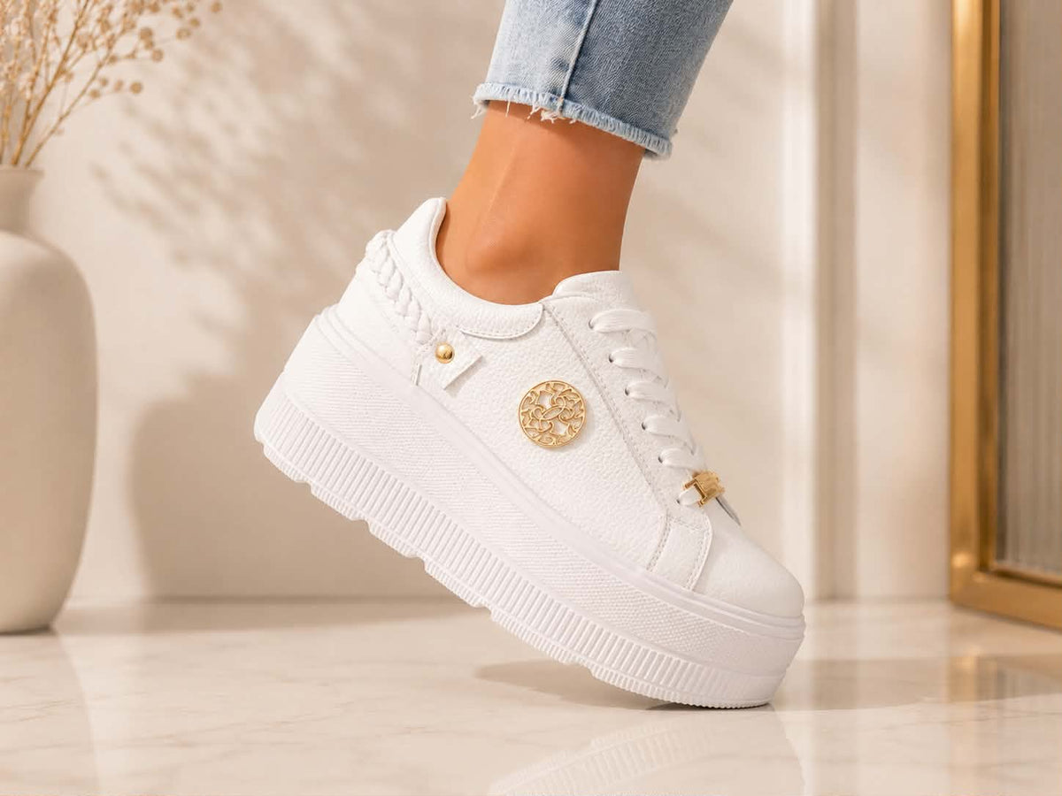 Białe sneakersy damskie Goodin ze skóry naturalnej na wysokiej platformie z ozdobnymi złotymi detalami. Modne buty sportowe do codziennych i eleganckich stylizacji, zapewniające wygodę i nowoczesny wygląd.
